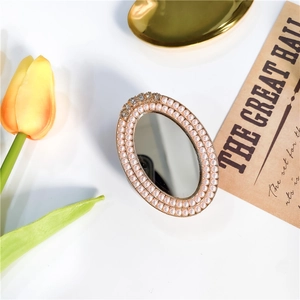 Detail of oval makeup mirror with pink pearls, gold base and sparkling diamonds