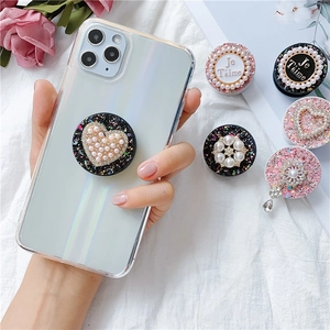 Schicker Handy-Grip mit Perlenherz und Glitzer auf elegantem weißem Stoff drapiert