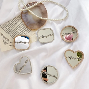 Detailed view of heart and round mirror phone grips with sparkling rhinestones and silver finish