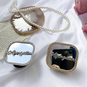 Detail showing gold and silver rhinestone phone grips with heart mirror on white fabric