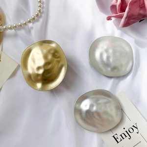 Detail of hammer-textured metal jewelry set on white silk with pearls and floral accents