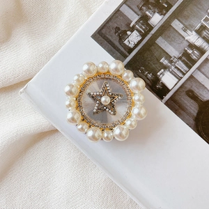 Detail of a round folding phone stand with faux pearls and golden star on a white book
