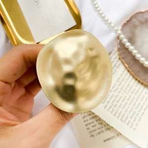 Macro detail of vintage gold metal phone grip with artistic hammered texture and wavy edges