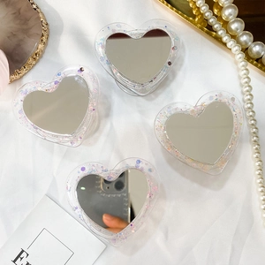 Détail du support de téléphone cœur à paillettes avec miroir sur tissu blanc