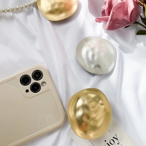 Detail of creative irregular hammered metal phone grips in gold and silver finishes