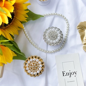 Macro shot of pearl and rhinestone floral phone grips on elegant silk background