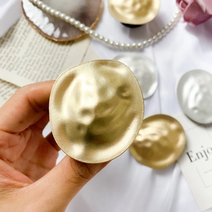 Close-up of gold and silver phone grips with hammered metal texture on silk background