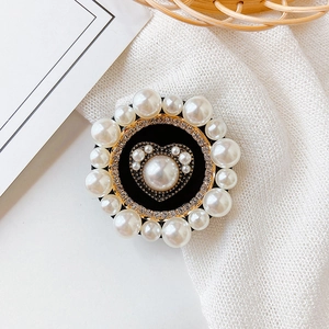 Macro detail of rhinestone and pearl heart phone grip on a minimalist fabric background