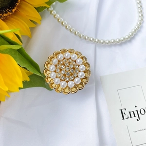 Close-up of sunflower phone grip featuring white pearls and crystals on gold base