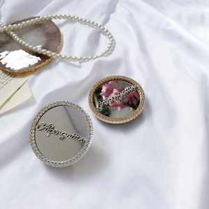 Close-up of gold and silver rhinestone phone ring holders with mirror surface on silk fabric