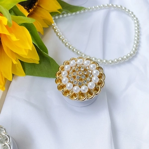 Detail of sunflower phone grip with pearls and rhinestones on white fabric