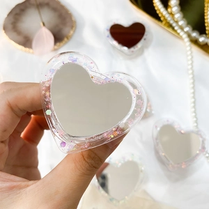 Détail d'un support de téléphone cœur pailleté avec miroir de maquillage intégré chic