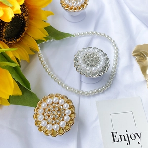 Detail view of pearl and rhinestone floral phone grips on elegant silk background