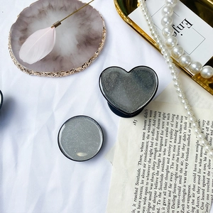 Supporto per telefono a cuore e rotondo con glitter argento su vassoio in marmo