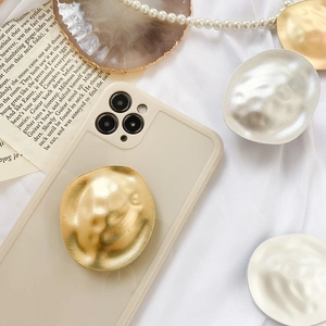 Detail of creative metallic phone grip with hammered texture on a beige case