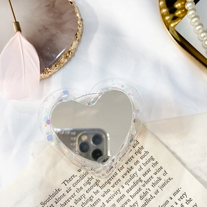 Gros plan d'un support de téléphone cœur avec paillettes et miroir sur fond esthétique