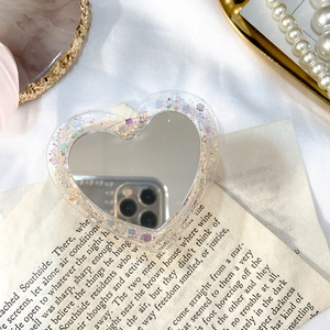Détail macro du support de téléphone cœur à paillettes avec miroir sur fond vintage chic