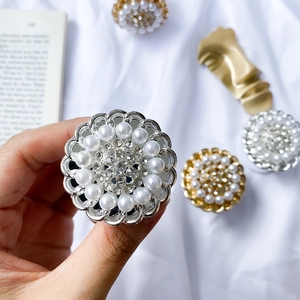 Detail of floral pearl and rhinestone phone grip holder on white velvet background