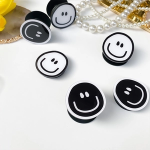 Macro view of white and black smiley face folding phone grips on a minimalist background