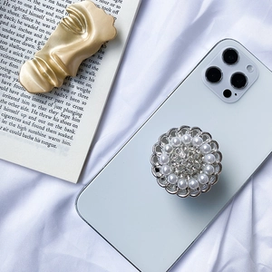 Close-up of a silver lace phone socket with pearls and rhinestones on a white smartphone
