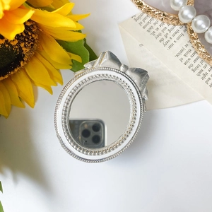 Close-up of vintage silver bow mirror stand with pearl details and floral decor