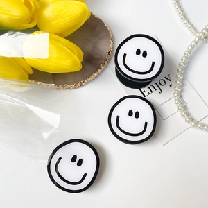 Close-up of three creative DIY smiling face phone grips on a minimalist white table