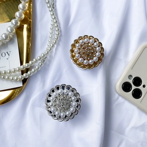 Detailed macro view of pearl and rhinestone floral cell phone grip holders in gold and silver