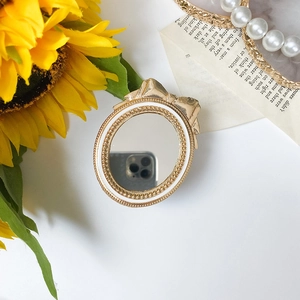 Detail of vintage gold bow mirror phone stand with pearls and rhinestones on sunflower base