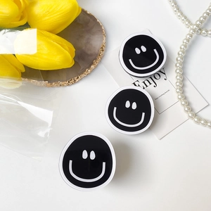 Three minimalist black and white smiley face phone grips set on a marble surface decor