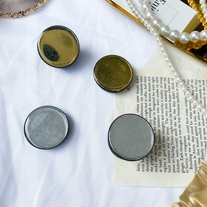 Dettaglio dei supporti per telefono glitterati in oro e grigio su un panno bianco