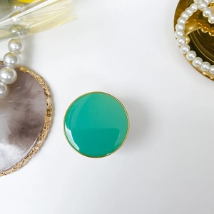 Detail of emerald green adhesive folding phone grip with elegant gold metal rim
