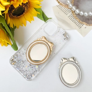 Detail of glitter phone case with vintage mirror socket and golden bow decoration
