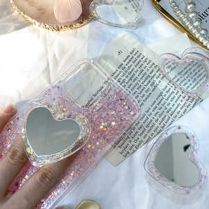 Coque de téléphone à paillettes roses avec support miroir en forme de cœur sur un livre
