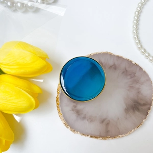 Supporto pop socket blu lucido con bordo dorato su vassoio di marmo con tulipani