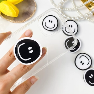 Detail of creative DIY smiley face phone grip on a transparent case with aesthetic props