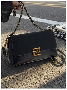 Détail d'un sac à bandoulière noir avec boucle dorée et matières en cuir texturé