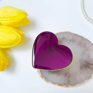 Dettaglio di un vassoio per gioielli in ceramica viola a forma di cuore con bordo dorato lucido