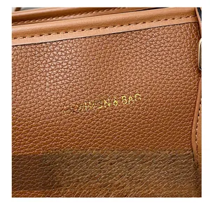 Close-up of brown litchi pattern leather bag featuring gold fashion letter printing
