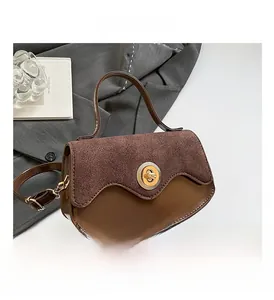 Detail of brown suede patchwork shoulder bag with wave-edge flap and gold rotary lock