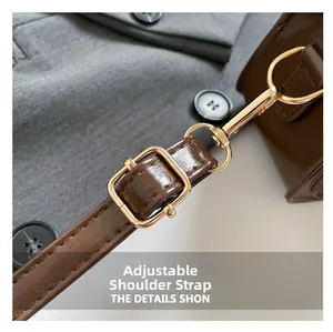 Detail of adjustable dark brown leather shoulder strap with golden metal buckle and clasp