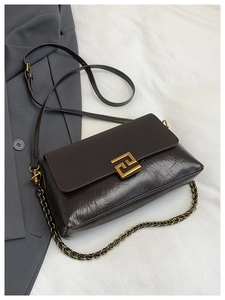 Detail of vintage pleated leather handbag with golden geometric lock and chain strap