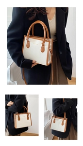 Detail of minimalist white lychee texture bag with brown leather trim and shoulder strap