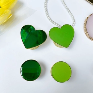 Dettaglio di supporti per telefono a cuore e tondi in resina verde con base in metallo dorato