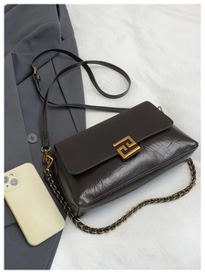 Détail du sac à bandoulière marron foncé avec boucle dorée et lanière en chaîne