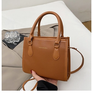 Detailed view of brown litchi textured leather tote with fashion print and sleek handles