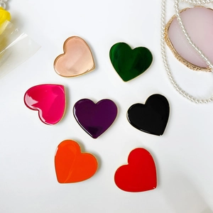 Dettaglio di supporti per telefono a forma di cuore con smalto colorato e bordi dorati