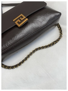 Détail du sac en cuir ciré marron avec grande boucle dorée et bandoulière en chaîne