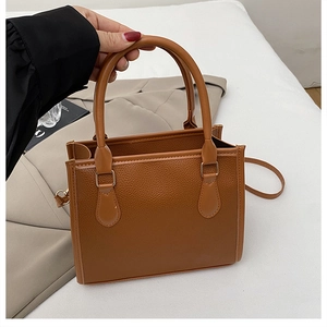 Detail of brown litchi pattern leather tote with light gold hardware and slim strap
