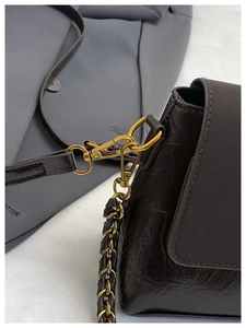 Gros plan d'un sac bandoulière marron foncé en cuir vintage avec boucles dorées mates