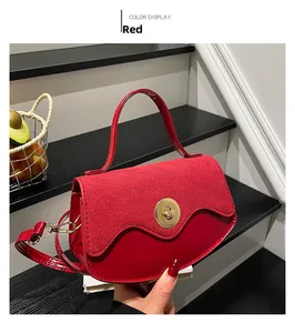 Detail of red leather crossbody bag with wave flap and gold metal circular twist lock